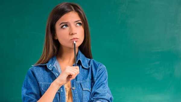 Female student holding pencil near her mouth deep in thought